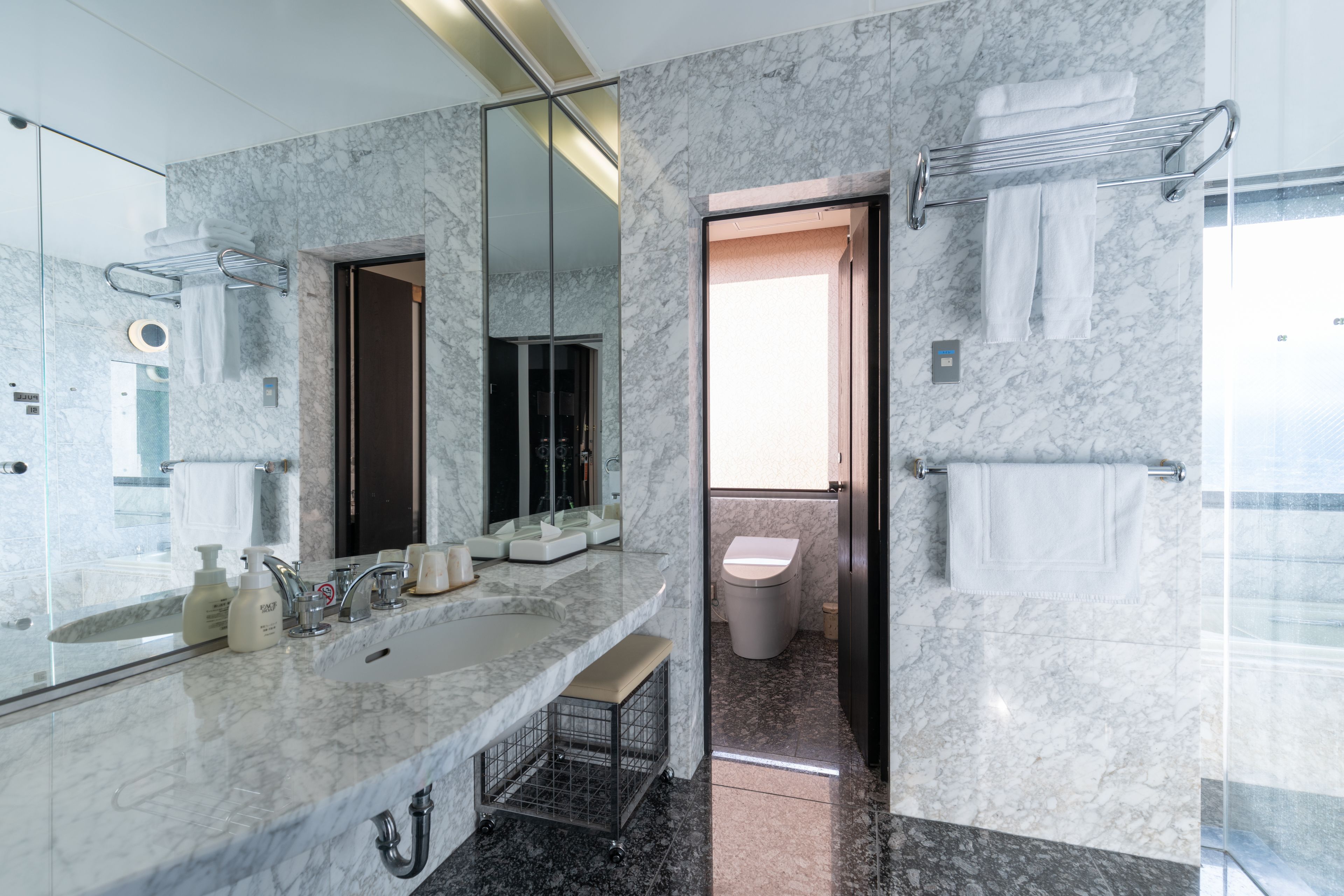 A modern bathroom with a marble sink, a large mirror, and a glass-enclosed shower area.