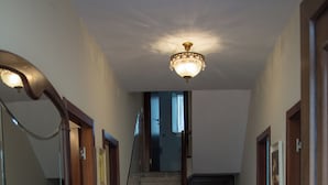 Un pasillo con una escalera de madera, un espejo, un armario de madera y una alfombra estampada.