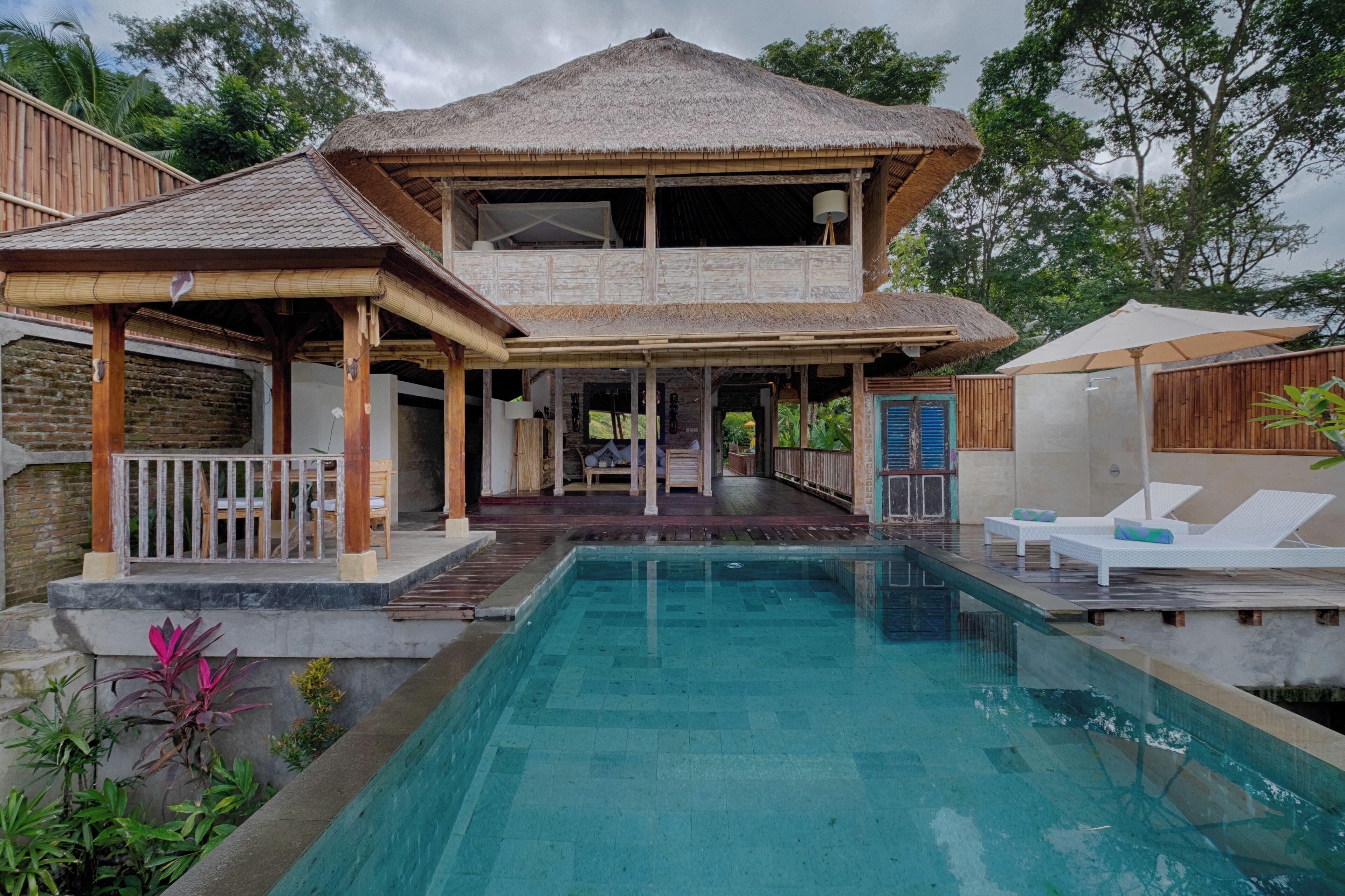 Una piscina al aire libre, sombrillas, sillones reclinables de piscina