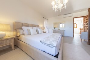 Un dormitorio con una cama grande, mesitas de noche, una araña, un espejo y un armario.