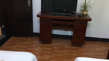 Una habitación con dos camas, un escritorio de madera con una computadora y una planta en maceta.