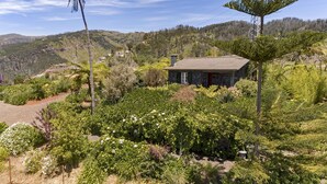 A stone house with a tiled roof surrounded by lush greenery and hills in the background. - Quinta Devónia - Cedro,country house with sea view (Funchal)