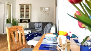 A modern living room with a sofa, dining table, and a cabinet. - *Anker Vacation Rental at Villa Victoria - GM 69836 - *Anker Vacation Rental at Villa Victoria (Graal-Müritz)