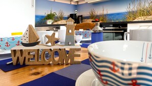 A kitchen with a nautical theme, including a 'WELCOME' sign, wooden cutouts, and a coastal mural. - *Anker Vacation Rental at Villa Victoria - GM 69836 - *Anker Vacation Rental at Villa Victoria (Graal-Müritz)