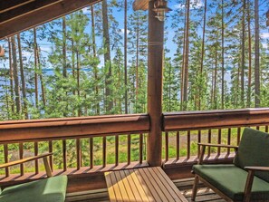 Eine Holzterrasse mit Geländer, zwei Stühlen und einem Tisch.
