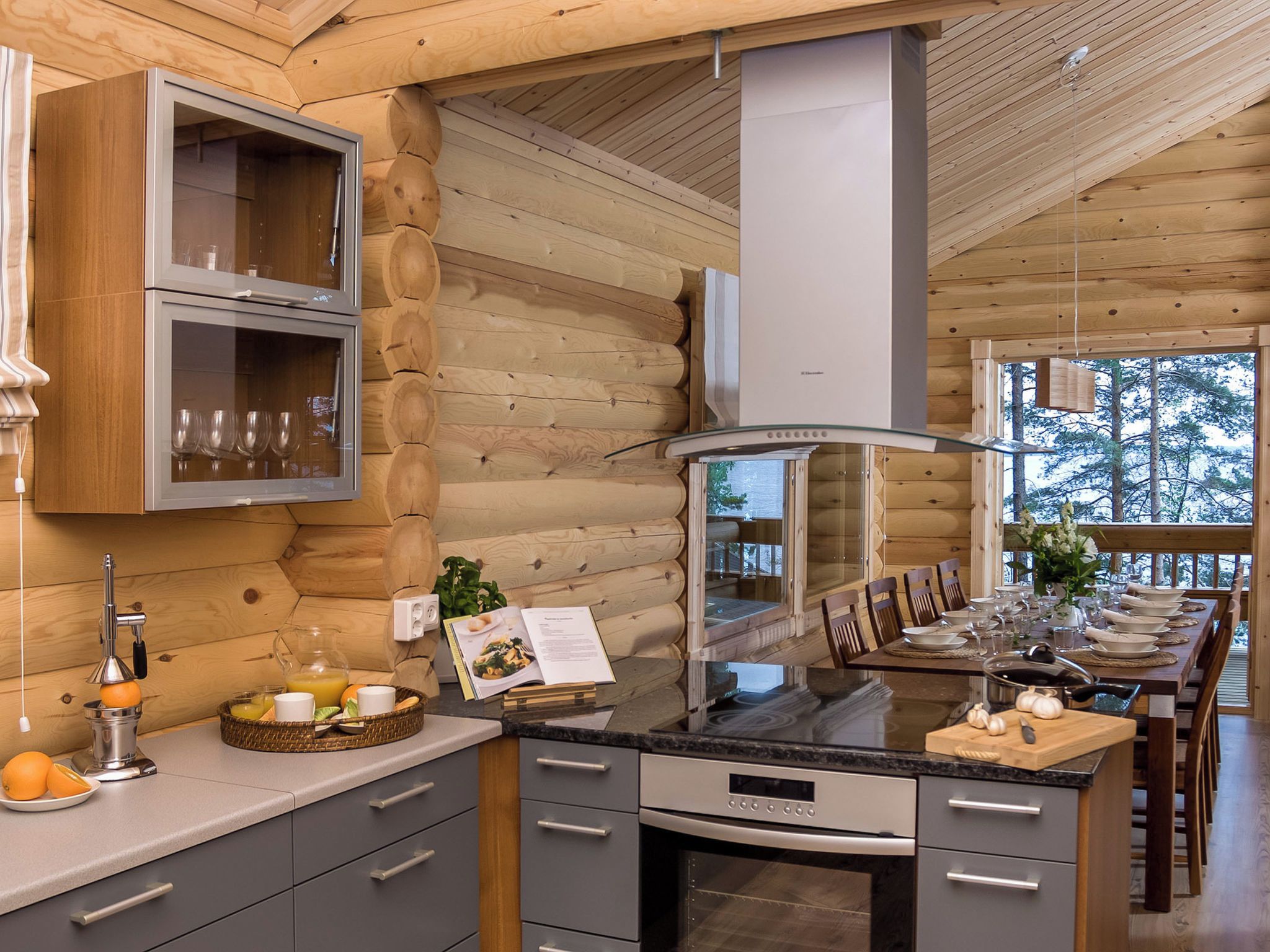 Een moderne keuken met houten wanden, een centraal eiland en een eethoek met uitzicht op bomen.