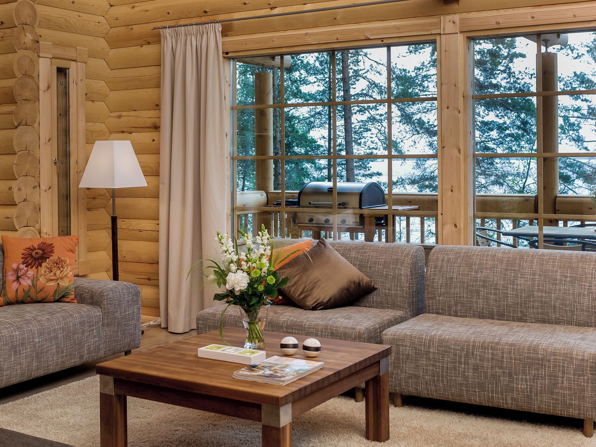 Ein gemütliches Blockhaus-Interieur mit einer Couch, einem Couchtisch und einem Fenster mit Blick auf einen Wald.