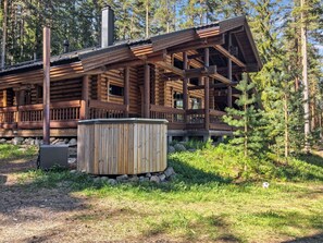Eine Blockhütte mit Veranda, Whirlpool und Steinmauer.