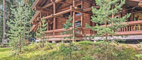 A log cabin with a porch, surrounded by trees.