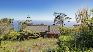 A house with a tiled roof surrounded by lush greenery and wildflowers. - Quinta Devónia - Tília,country house with sea view (Funchal)