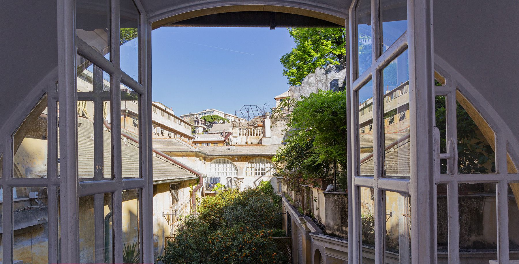 A view through a window of a building with multiple floors, featuring a staircase and a garden area.