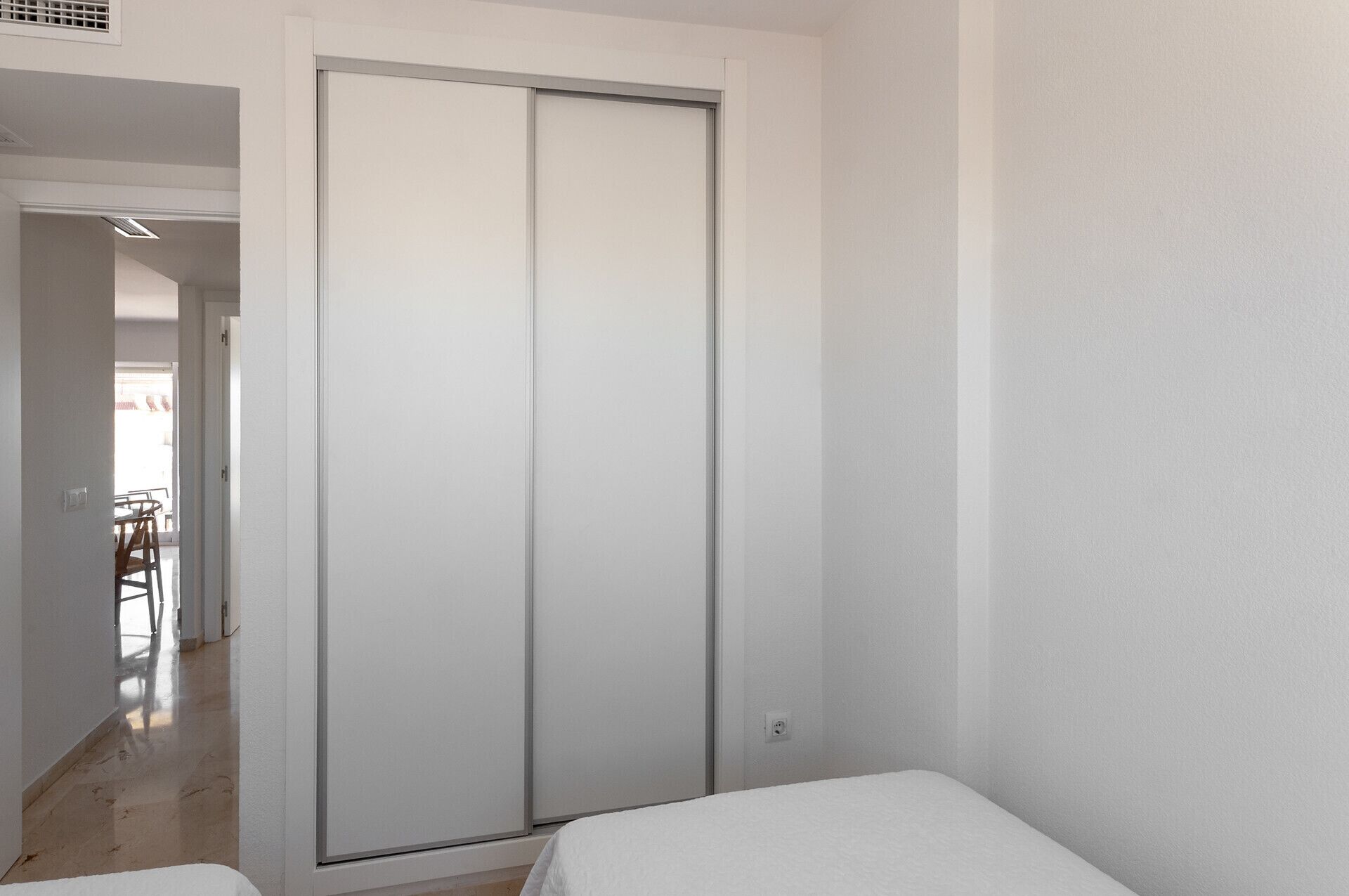 Une pièce dotée d’une porte coulissante, d’un lit et donnant sur un espace extérieur aménagé avec une table et des chaises.