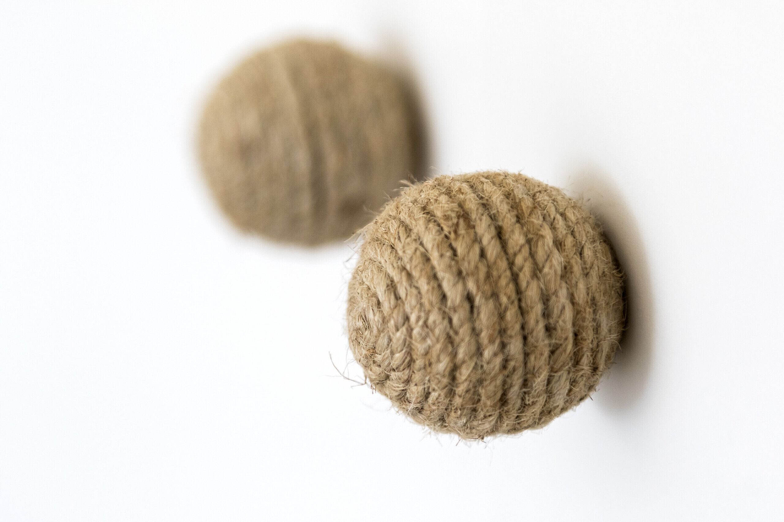 Two spherical objects with a textured surface, likely made of a fibrous material, against a plain background.