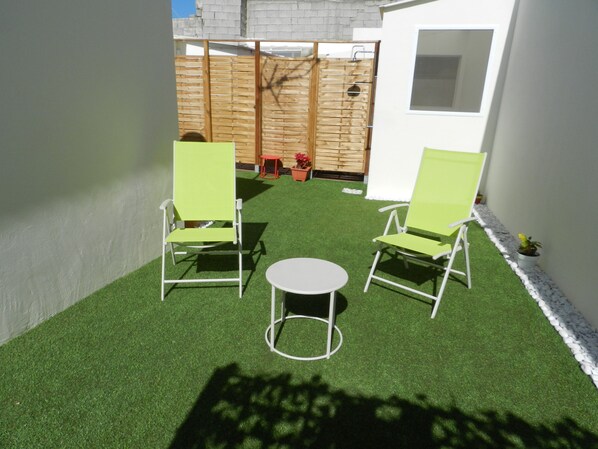 A small patio with two green chairs and a round table, surrounded by artificial grass. - TROTAMUNDOS GRAN CANARIA 2 (El Tablero)