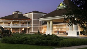 A hotel with a large outdoor area, a horse statue, and a sign for 'Saratoga Gaming and Raceway'. - Spacious, Cozy 5 Bedroom Compound  (Saratoga Springs)