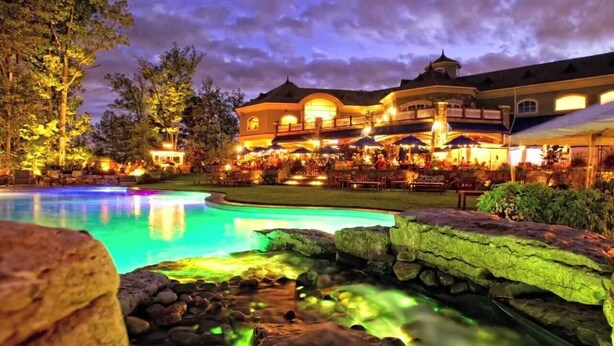 A large resort with a swimming pool, outdoor seating, and a well-lit building. - Spacious, Cozy 5 Bedroom Compound  (Saratoga Springs)