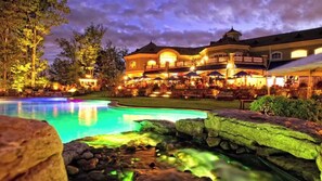 A large resort with a swimming pool, outdoor seating, and a well-lit building. - Spacious, Cozy 5 Bedroom Compound  (Saratoga Springs)