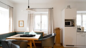 A dining area with a table, chairs, and a window with curtains.