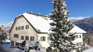 A snow-covered building with a sign reading "Greier's Apartments & Ferienwohnungen."