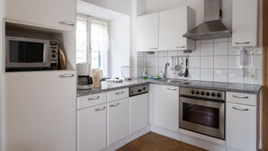A modern kitchen with white cabinets, a stainless steel oven, a microwave, and a coffee maker.