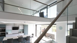 Een moderne keuken met een centraal eiland, barstoelen en een zithoek met een bank.