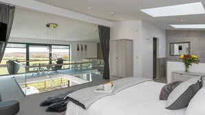 Een moderne hotelkamer met een groot bed, een balkon met uitzicht, een bureau en een badkamer met een spiegel.