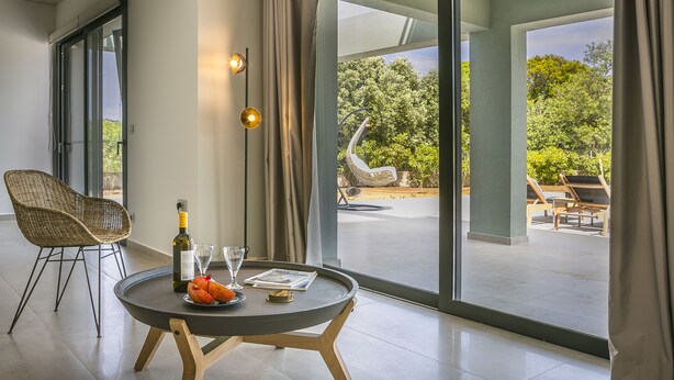 A modern room with a large sliding glass door leading to an outdoor area with lounge chairs and a view of greenery. - Villa Lantana is perfect for guests wishing to have a peaceful and pleasant stay (Skala)