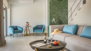 A modern living room with a sofa, two armchairs, a coffee table with a bottle, glasses, and fruit. - Villa Lantana is perfect for guests wishing to have a peaceful and pleasant stay (Skala)