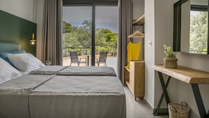 A modern hotel room with a large bed, a wooden desk, a small table with chairs, and a balcony with a view of greenery. - Villa Lantana is perfect for guests wishing to have a peaceful and pleasant stay (Skala)
