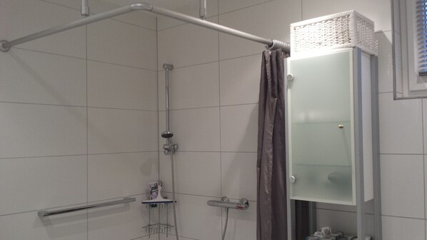A shower with a glass enclosure, a towel rack, and a showerhead.