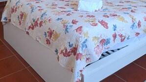 Une chambre à coucher comprenant un lit, un luminaire suspendu, une armoire en bois, un miroir et un élément décoratif fixé au mur.
