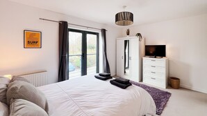 Un dormitorio con cama, armario, televisor y ventana con cortinas.