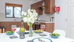 Una cocina moderna con armarios de madera, una mesa de comedor con platos, vasos y una botella de vino.
