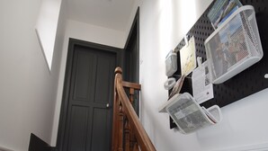 Una escalera de madera con barandilla, un tablero de corcho con varios objetos y una puerta en la parte superior.