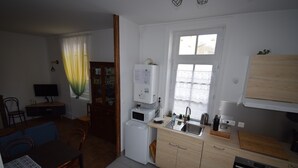 Una cocina compacta con refrigerador, microondas, lavamanos y armarios de madera.
