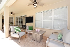 Relax in this cozy outdoor space with a ceiling fan, flat-screen TV, and comfortable seating for two.