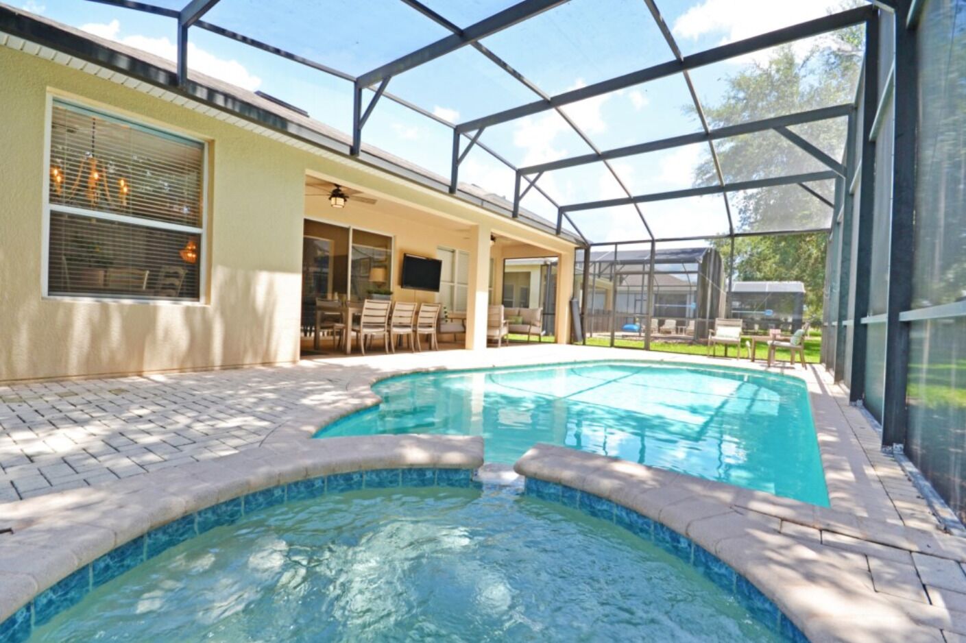 A swimming pool with a glass enclosure, patio furniture, and a view of the outdoors.
