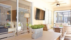 Un espace repas comprenant une table, des chaises, un téléviseur et un ventilateur de plafond.