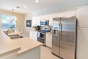 Enjoy cooking in this well-equipped kitchen with a central island, sink, and stainless steel appliances.