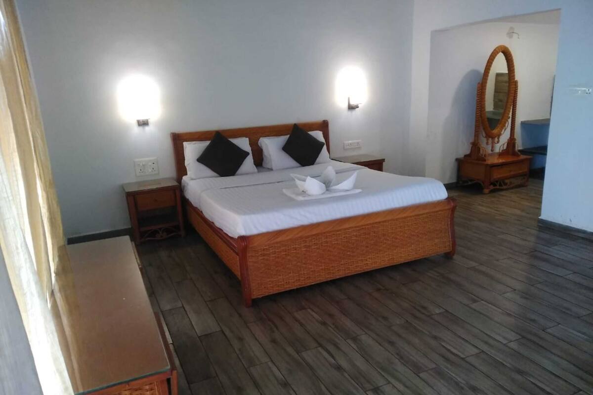 Un dormitorio ordenado con una cama de madera, dos mesitas de noche, un espejo y un pequeño aparador de madera.