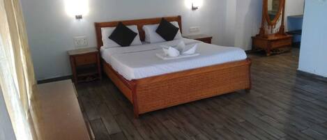 A neatly arranged bedroom with a wooden bed, two bedside tables, a mirror, and a small wooden dresser.