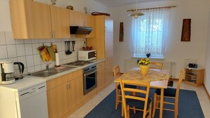 A compact kitchen with wooden cabinets, a microwave, stove, and a dining table with chairs. - Beautiful apartment in the Müritz National Park to relax and unwind or active holidays. (Federow)