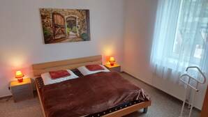 A bedroom with a bed, two bedside tables with lamps, a painting on the wall, and a window with curtains. - Beautiful apartment in the Müritz National Park to relax and unwind or active holidays. (Federow)