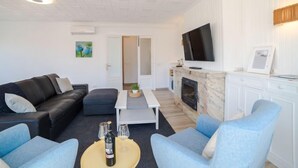 Una sala de estar moderna con un sofá, sillones, una mesa de centro, una chimenea y un televisor.