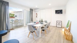 Un comedor moderno con una mesa blanca, sillas grises y suelo de madera.