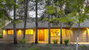Una casa de dos pisos con porche delantero, garaje y jardín bien cuidado.