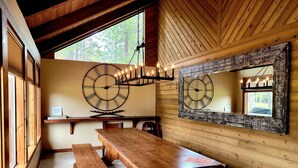 Un interior de madera con un reloj de pared grande, un banco de madera y una mesa.