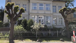 Un grand immeuble à plusieurs étages, doté d’une façade symétrique, de grandes fenêtres et d’un balcon bien visible.