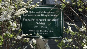 Un panneau vert avec du texte blanc, entouré de branches fleuries.