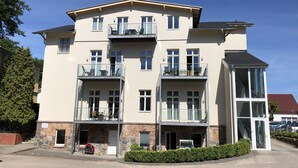 Un immeuble à plusieurs étages doté de balcons, d’un espace de stationnement et surplombant un ciel dégagé.